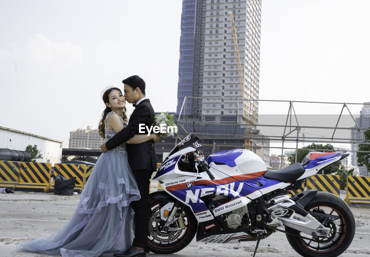 MAN WITH WOMAN STANDING AGAINST CARS