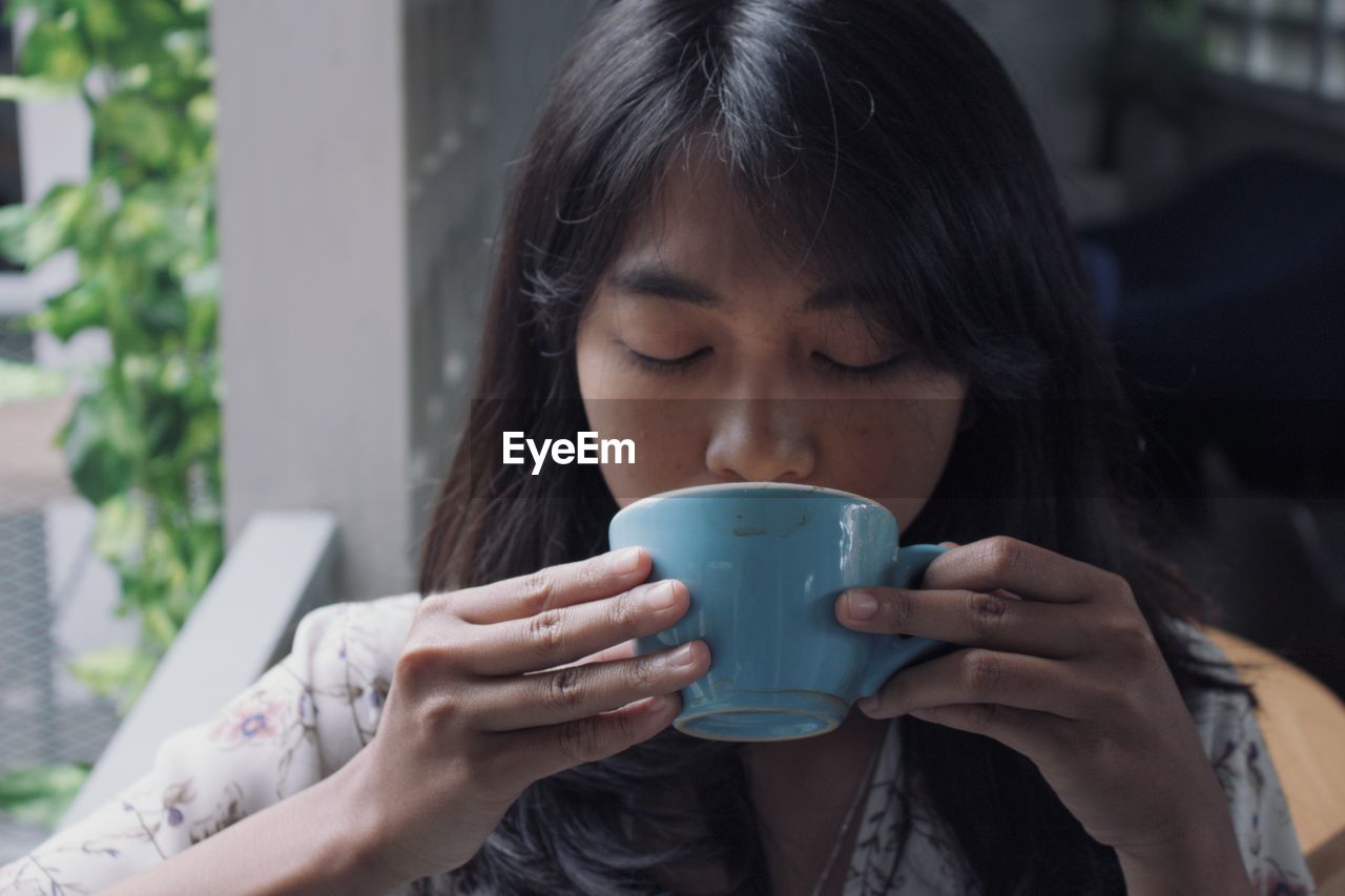 Close-up of young woman drinking coffee at home