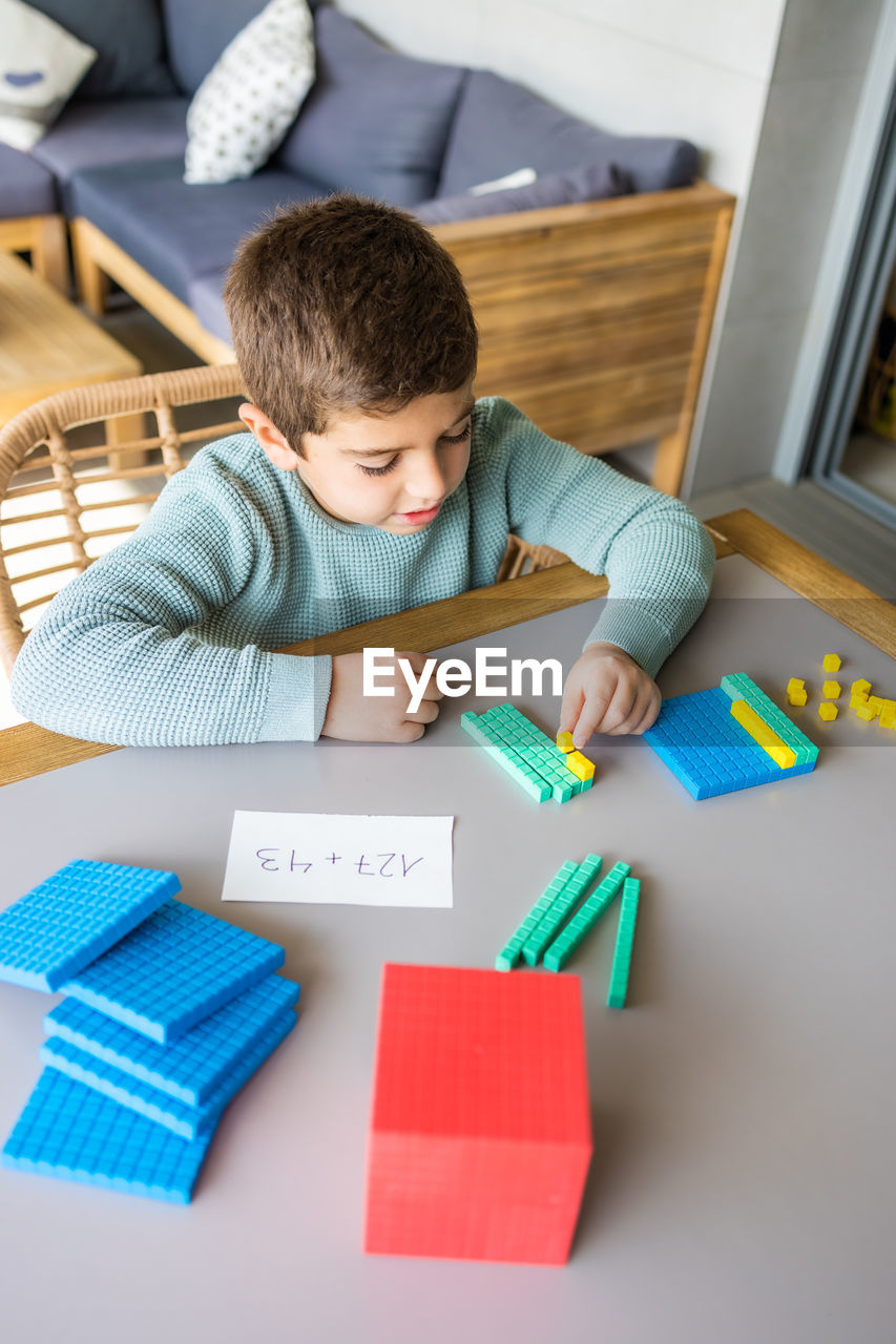 Little boy using the base 10 method to do addition at home