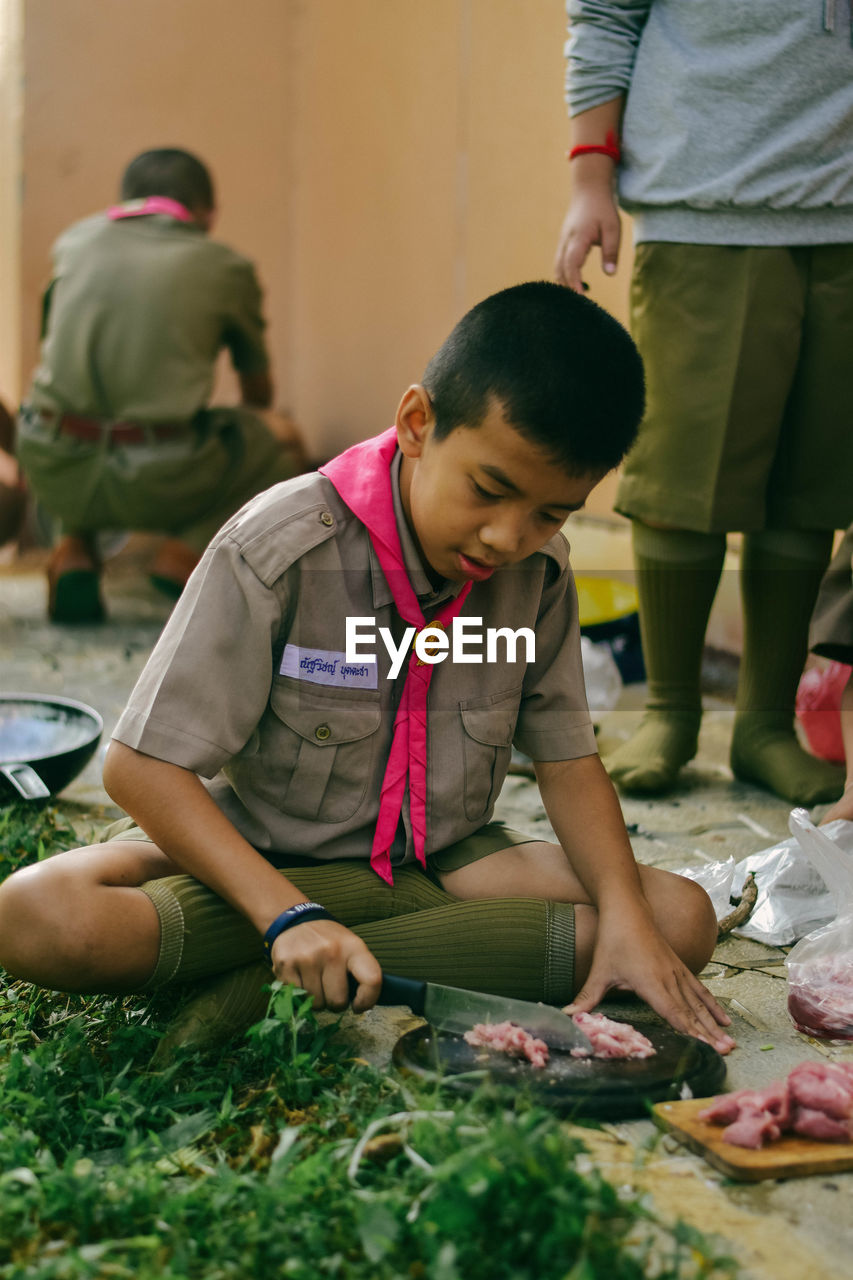 Boy cutting meat at outdoors