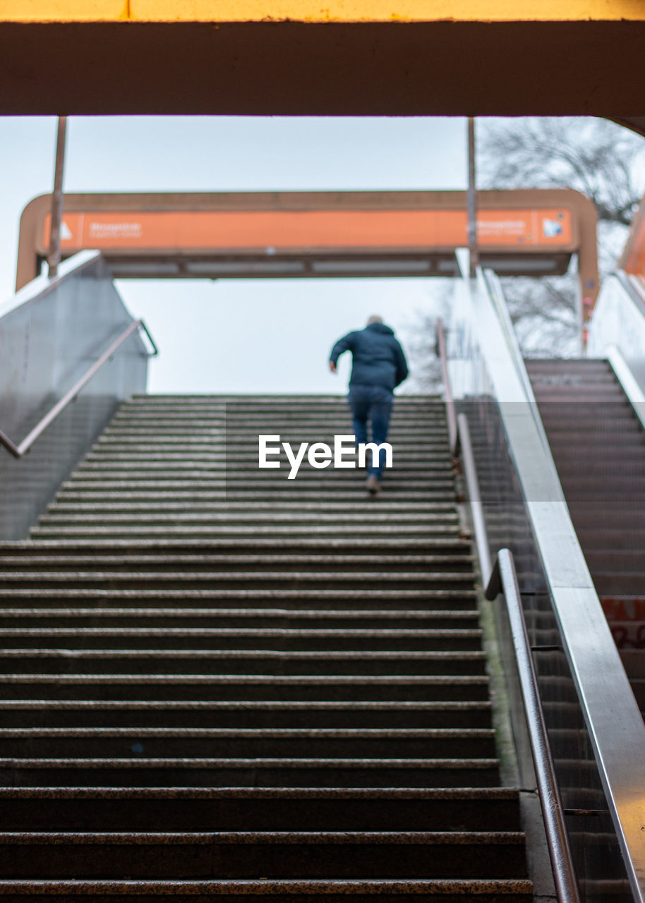 Rear view of man walking on escalator