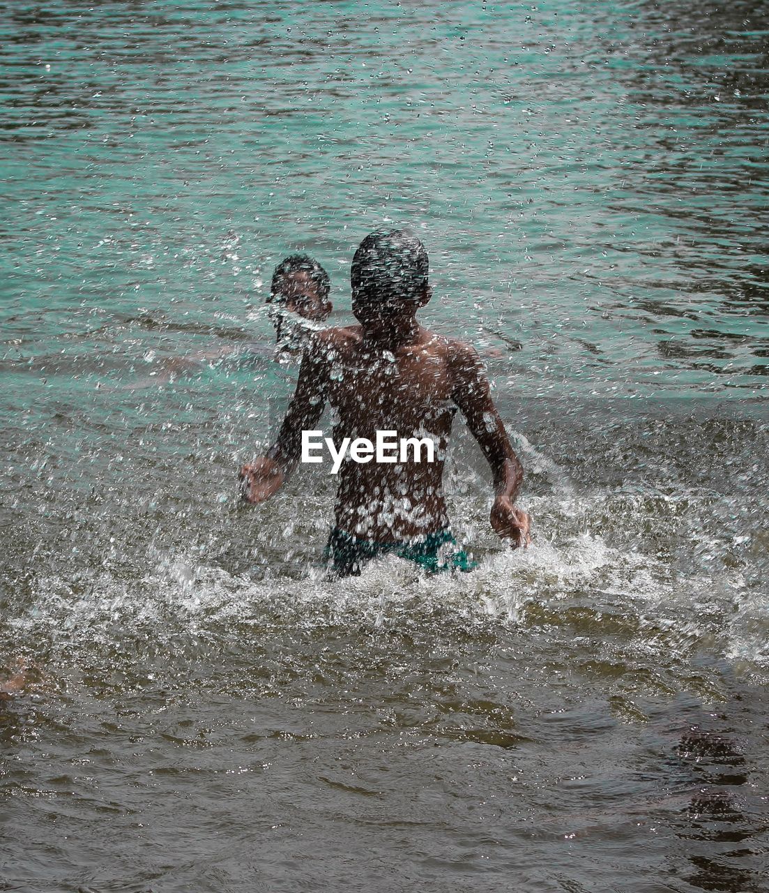 Full length of shirtless man splashing water