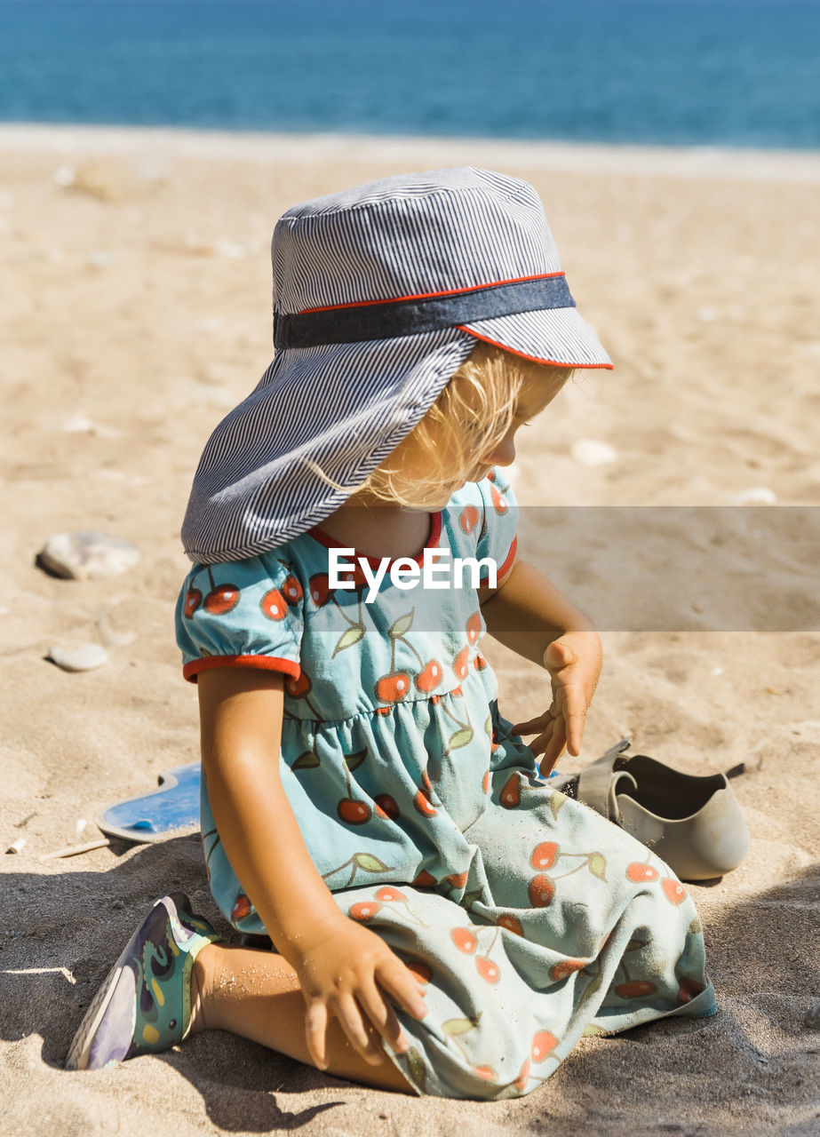 MIDSECTION OF BOY SITTING ON BEACH