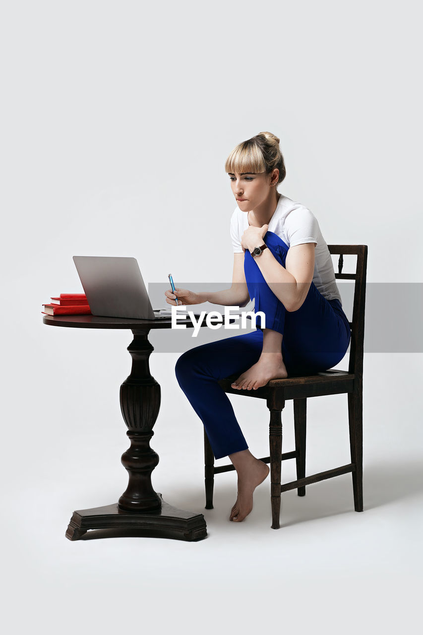 young woman using laptop while sitting on sofa