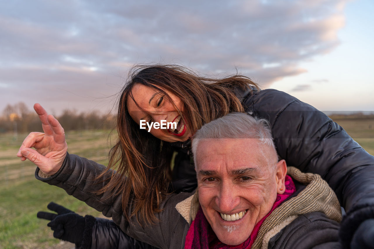 Middle aged couple wearing winter clothes taking a selfie in the countryside - people in recreation