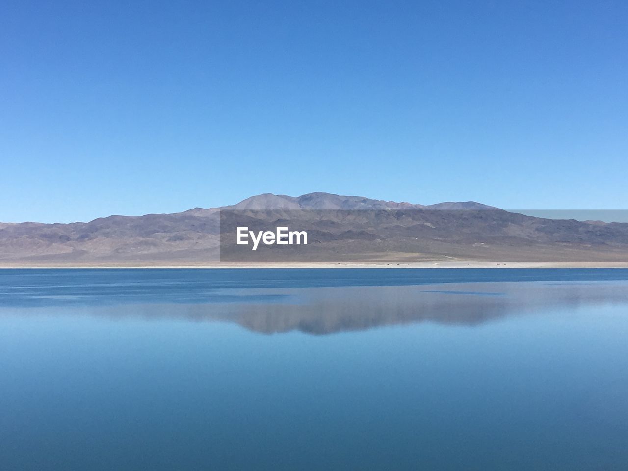 Scenic view of lake against clear blue sky