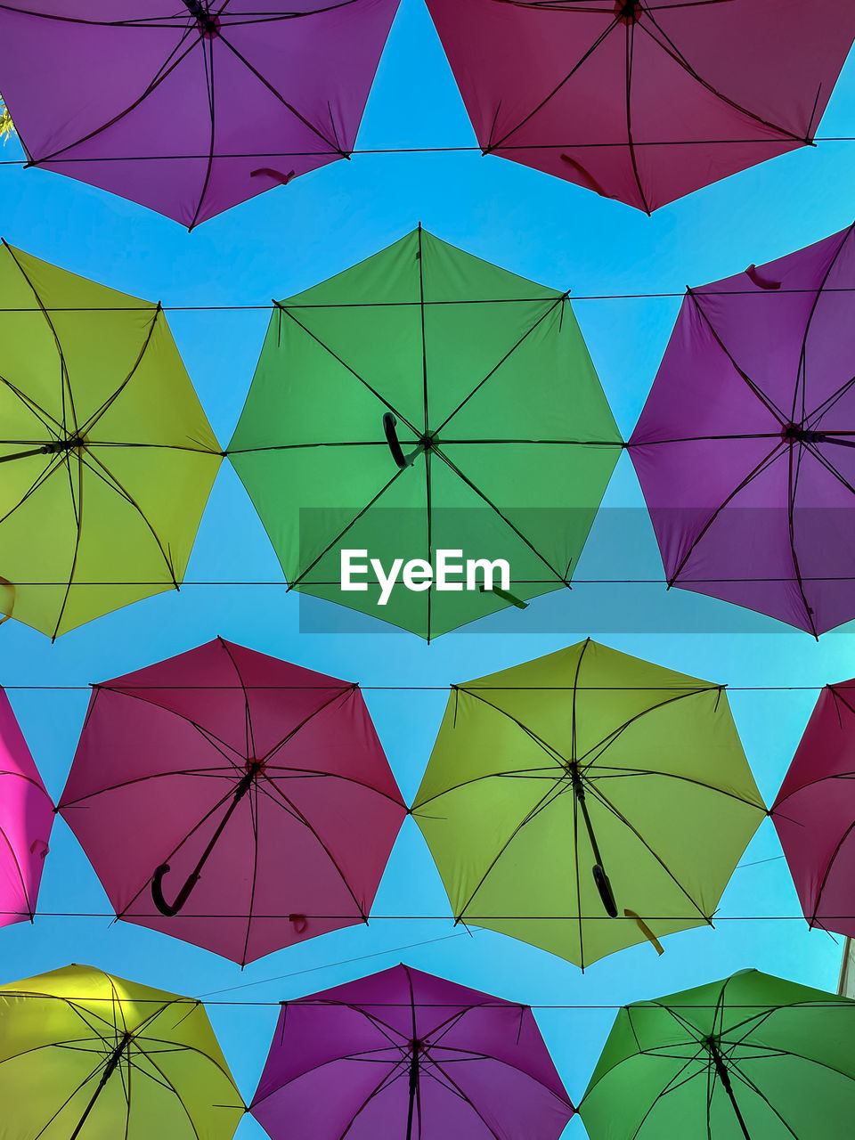 LOW ANGLE VIEW OF MULTI COLORED UMBRELLAS HANGING ON CLOTHESLINE