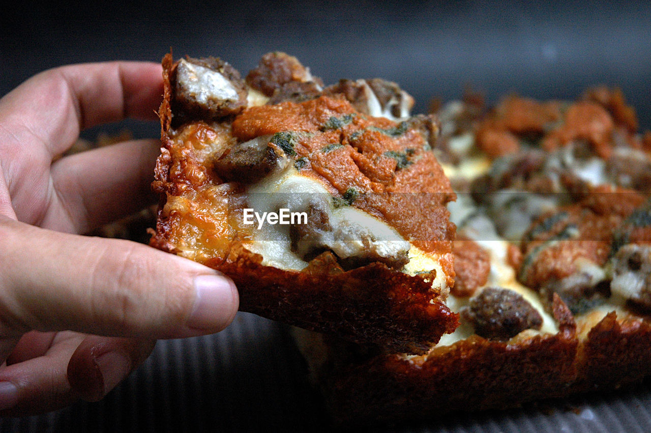 Close-up of hand holding detroit style pizza