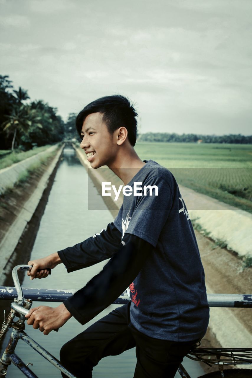 SIDE VIEW OF YOUNG MAN LOOKING AWAY IN BICYCLE