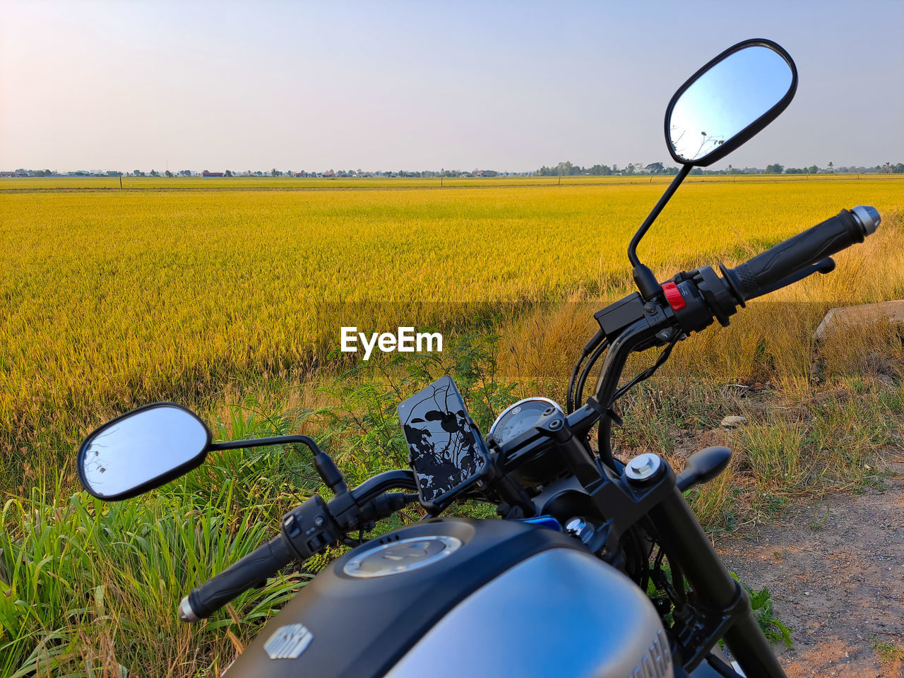 Bicycle parked on field by road against sky