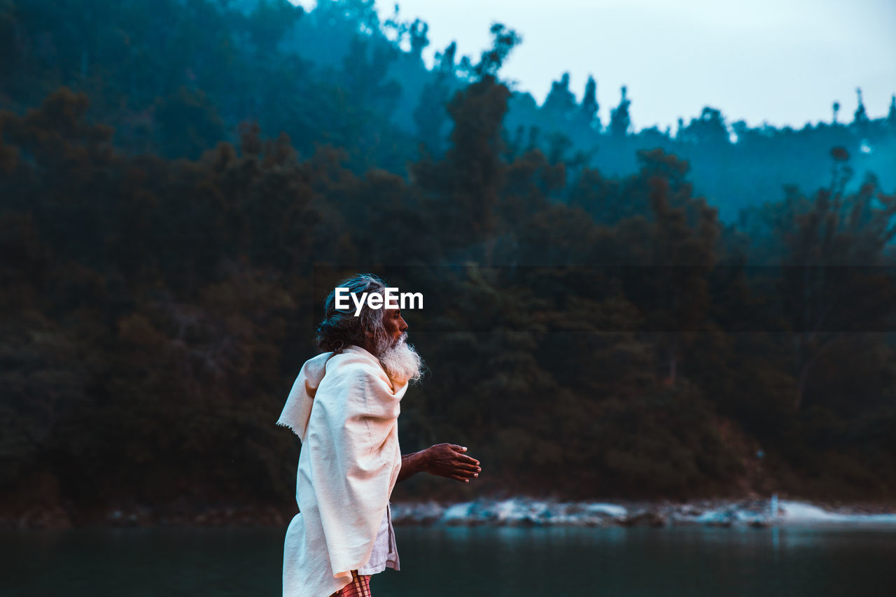 SIDE VIEW OF WOMAN STANDING BY LAKE