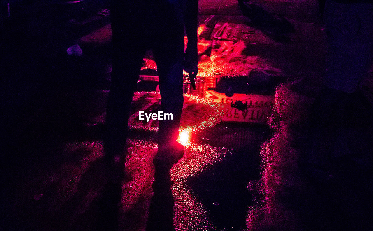 Silhouette man standing on wet road at night