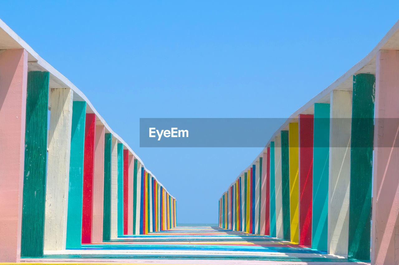 Low angle view of multi colored wooden footbridge against sky