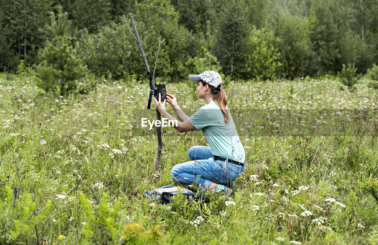 Young woman scientist sets camera trap for observing wild animals in forest environmental protection