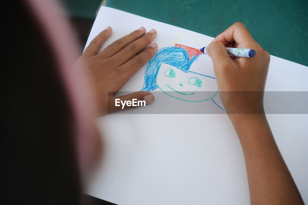 High angle view of girl drawing on paper