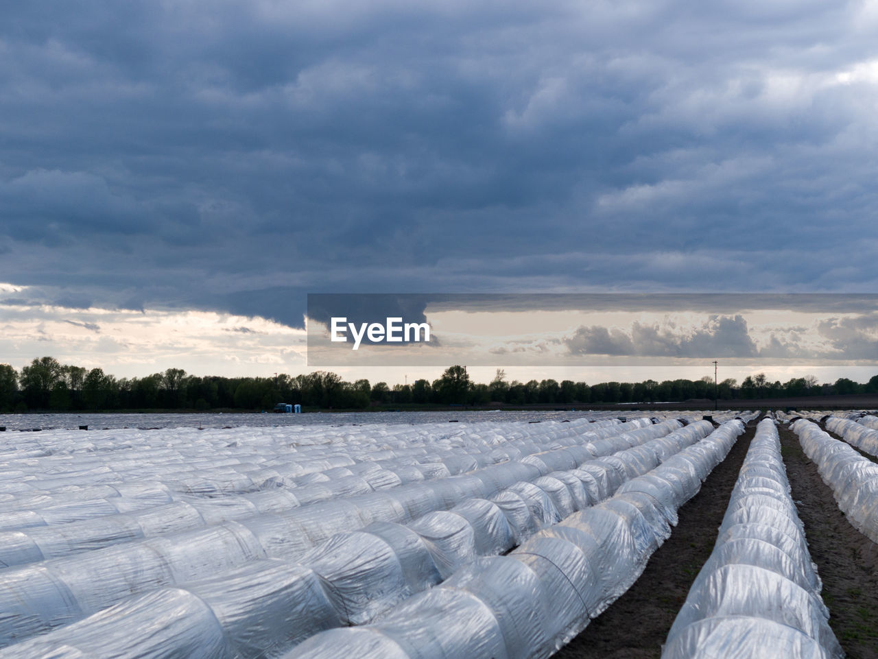 Scenic view of farm against dramatic sky