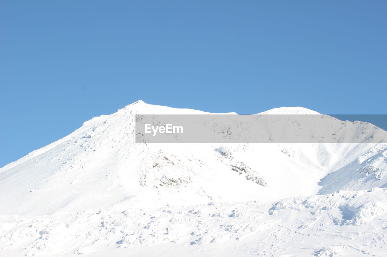 Scenic view of snowcapped mountains against clear blue sky