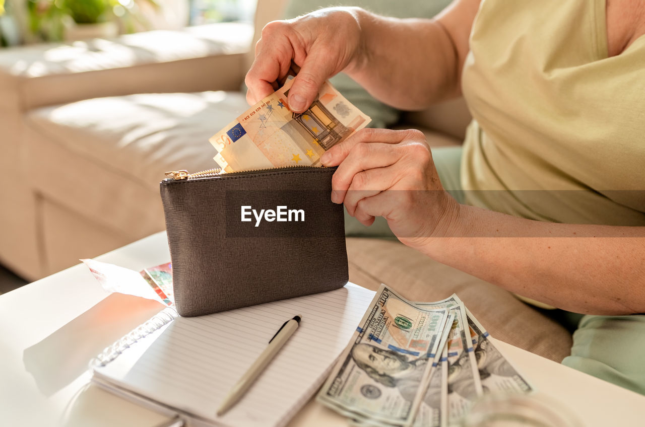 Senior woman hands putting euro money in wallet. pensioner counting savings and expenses 