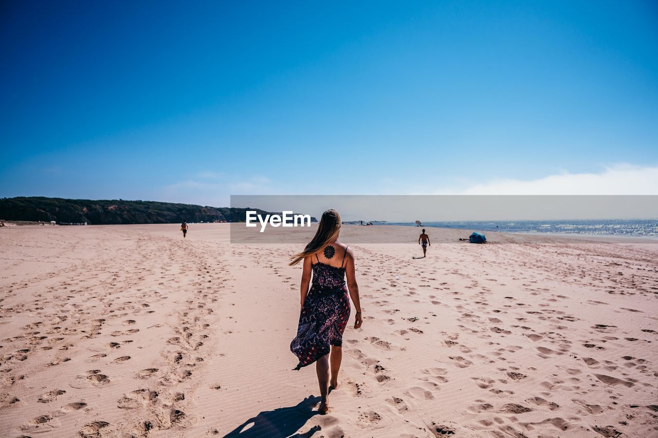 Rear view of woman walking at beach