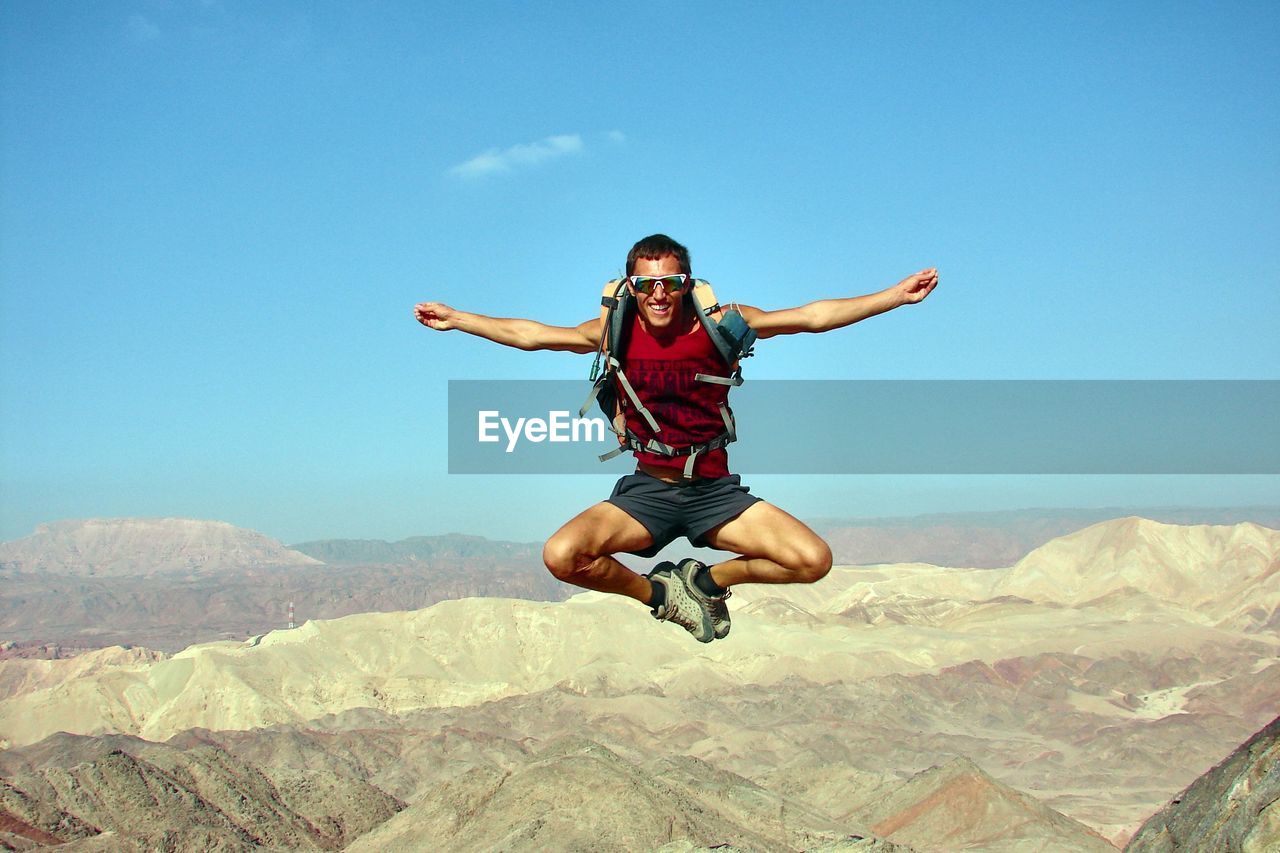 Full length of man jumping over landscape against sky