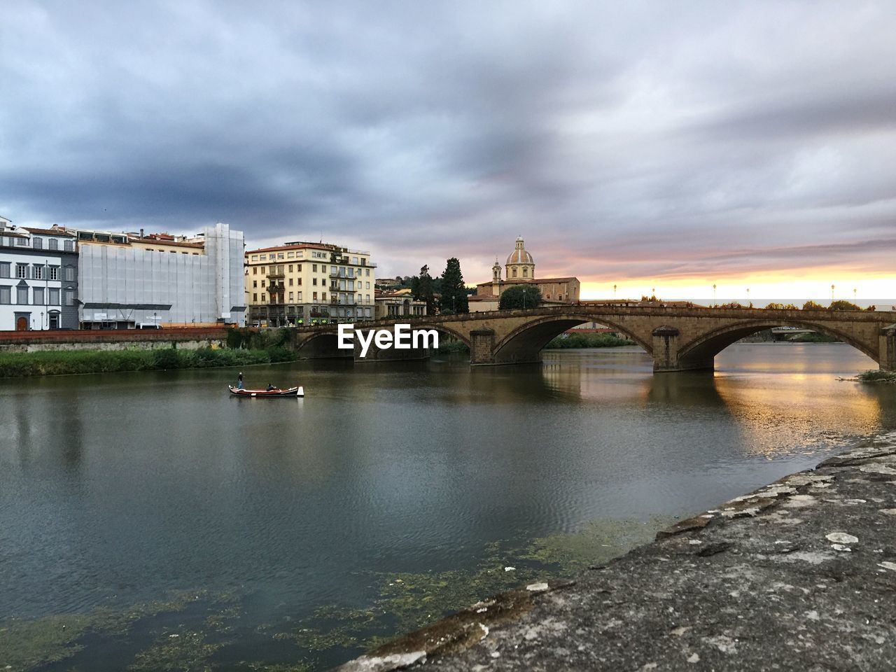 Arch bridge over river against cloudy sky