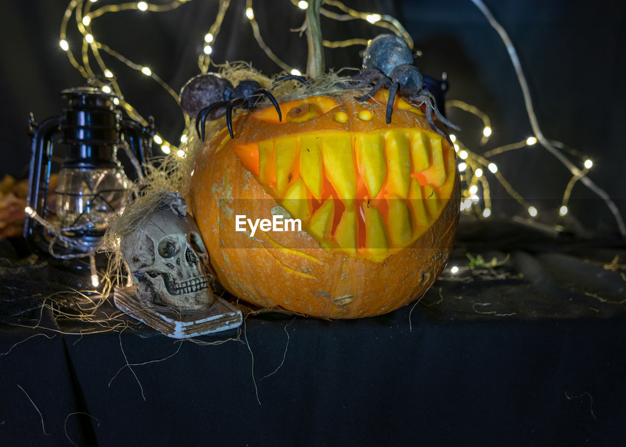 Carved pumpkin with a scary smile, spiders and cobwebs, awful skulls, decoration and holiday concept