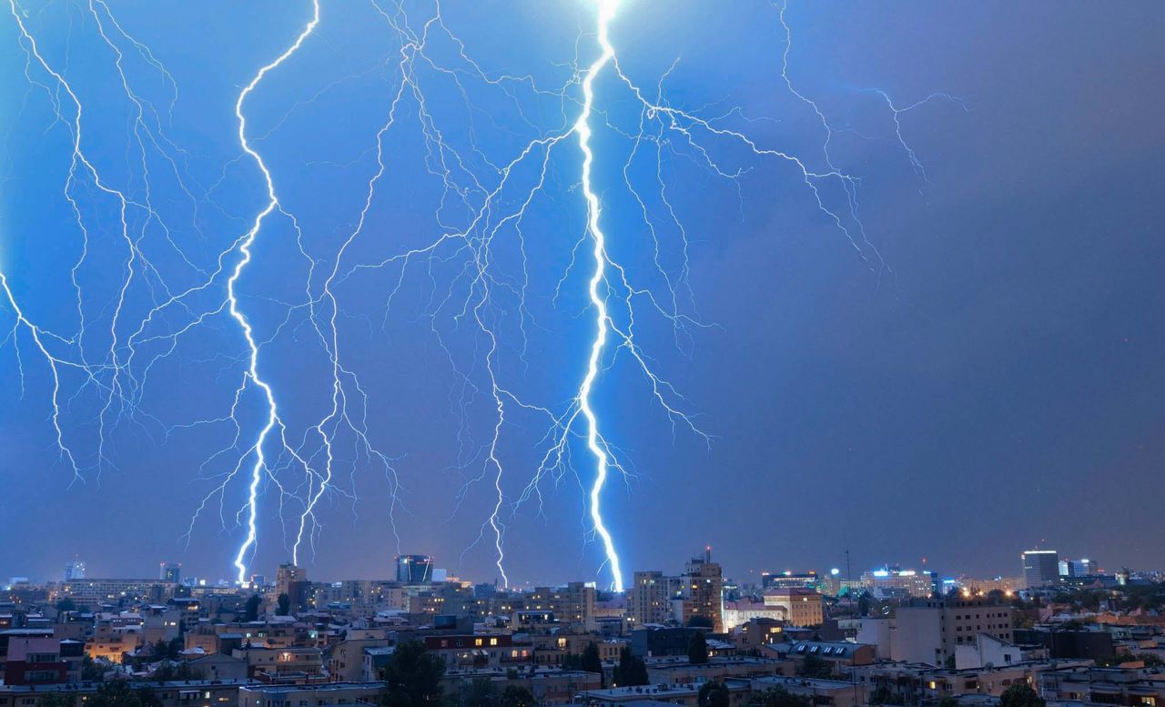 Lightning over cityscape against sky