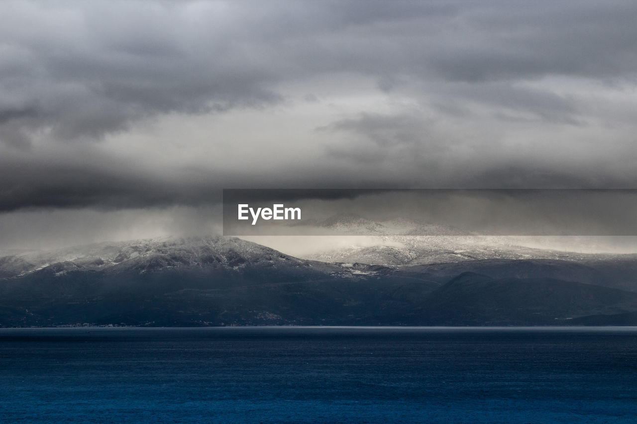SCENIC VIEW OF SEA AGAINST MOUNTAIN