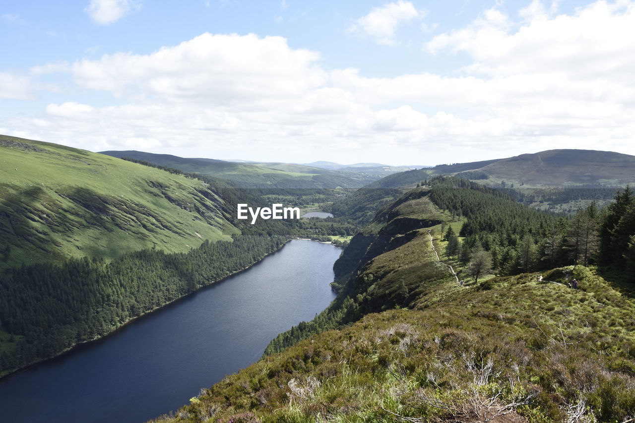 Scenic view of river by mountains against sky