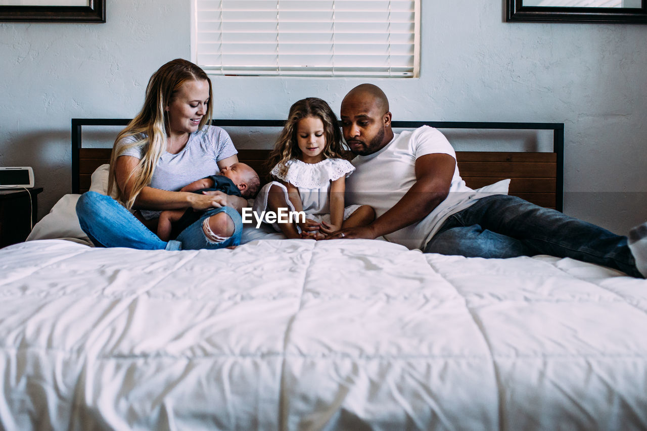 A family snuggling on the bed with newborn baby