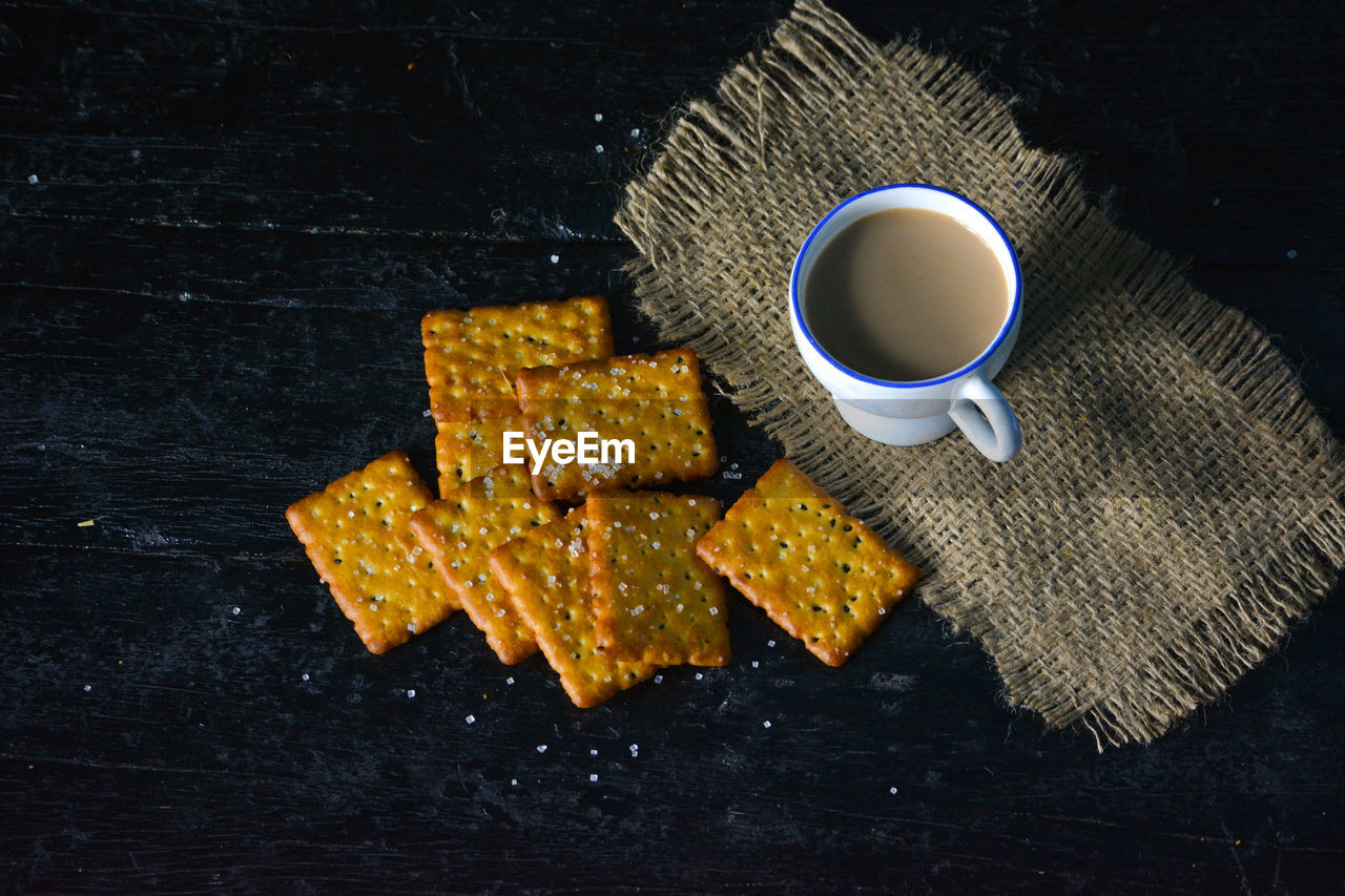 A cup of tea with biscuits on old wooden dark background