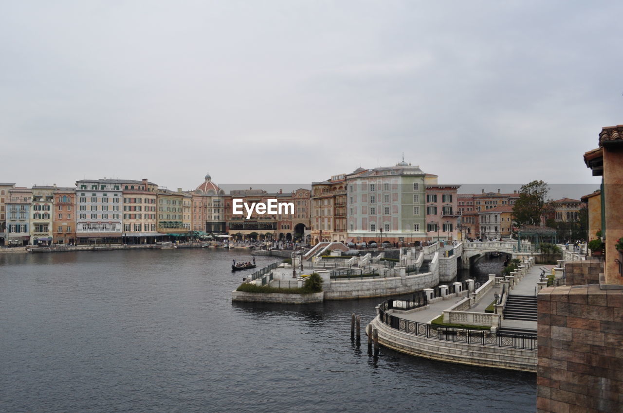 Boats in river by buildings in city against sky