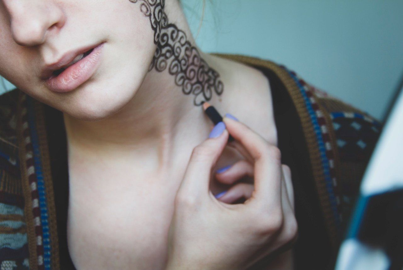 Close-up mid section of a woman drawing on her neck