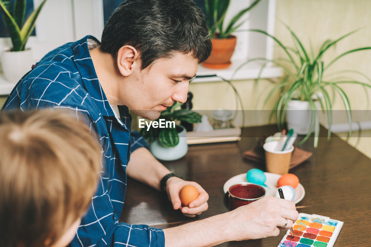 Easter day. father and son painting eggs. family preparing for easter, creative homemade decoration.