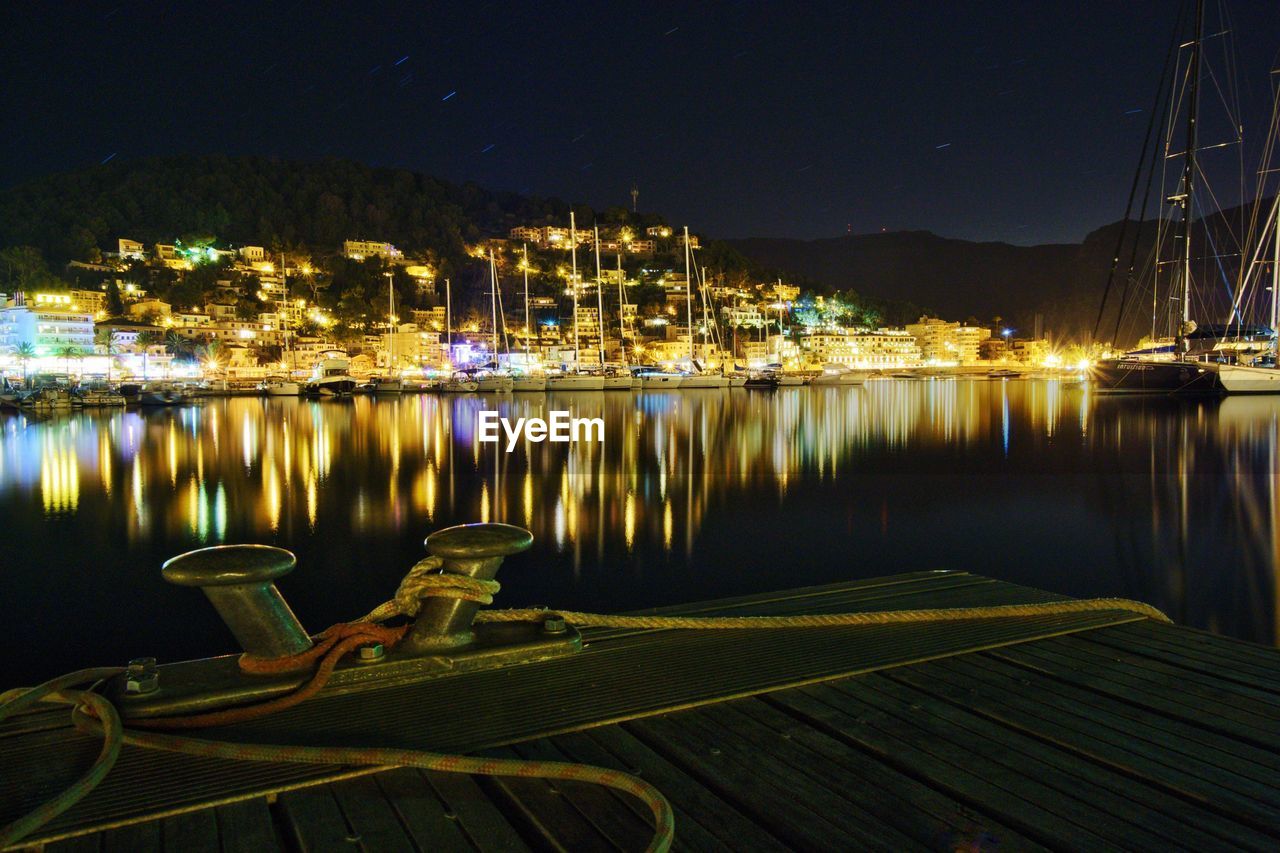 Illuminated moored boats in water at night