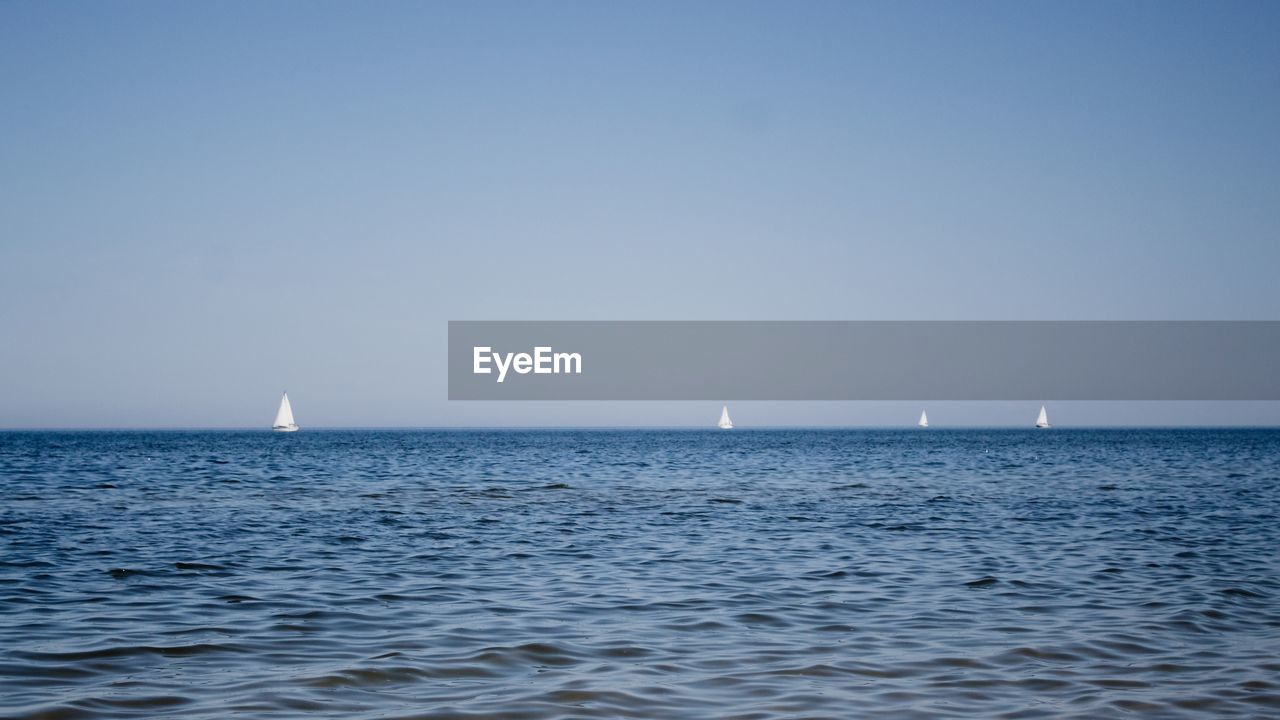 Sailboat sailing in sea against clear sky