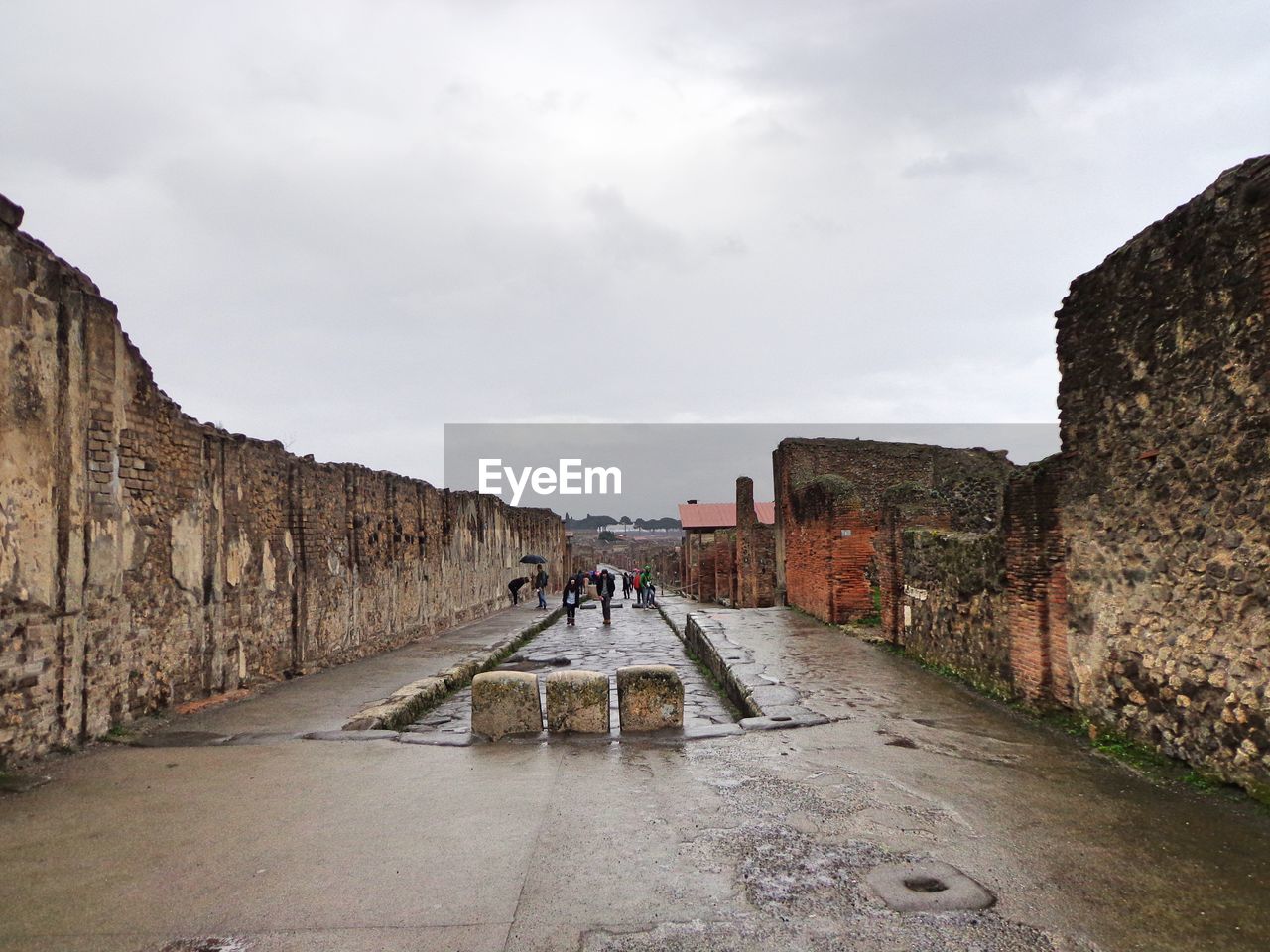 PEOPLE WALKING ON COBBLESTONE AGAINST SKY