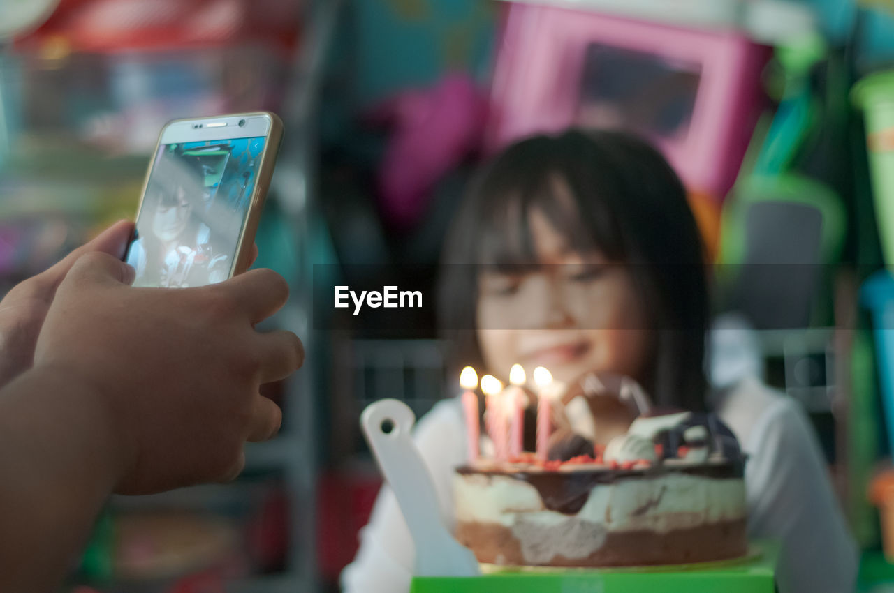 Close-up of cute girl sitting by cake at home