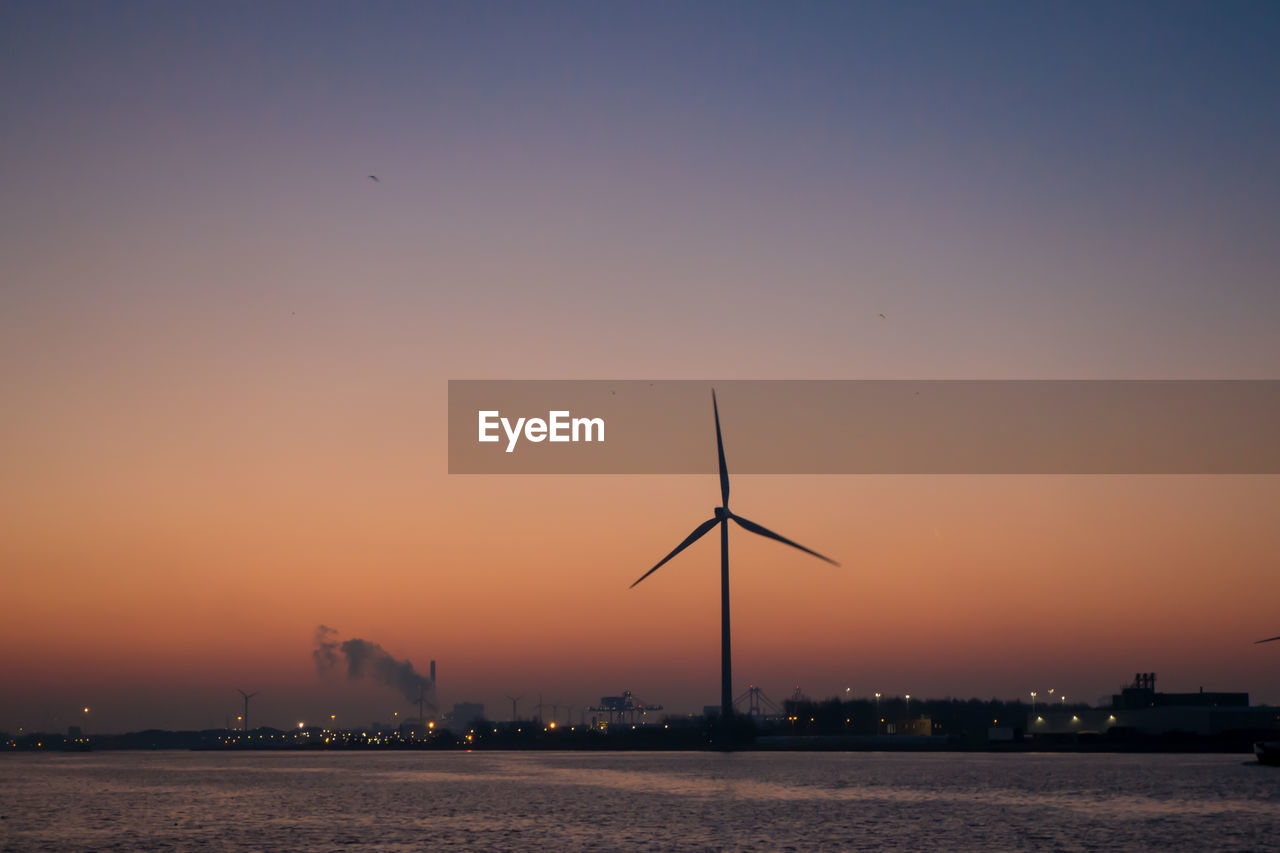 Silhouette of wind turbine against sky during sunset