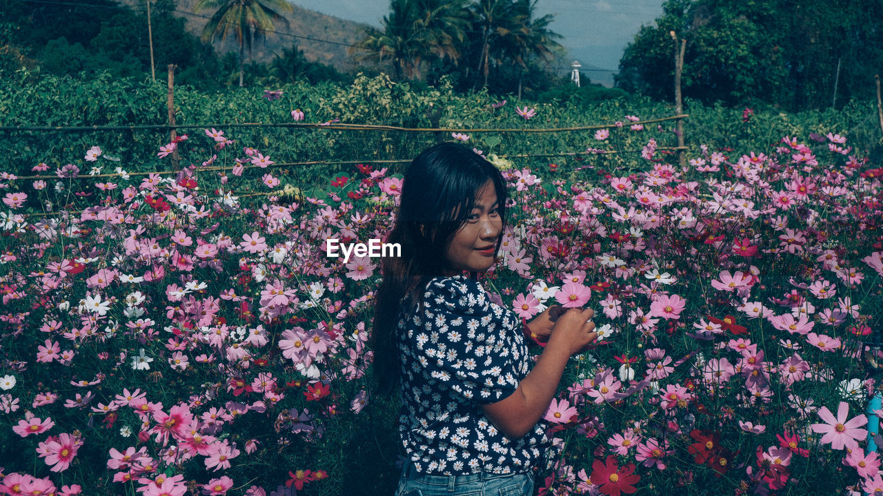 Full length of woman standing by flowering plants