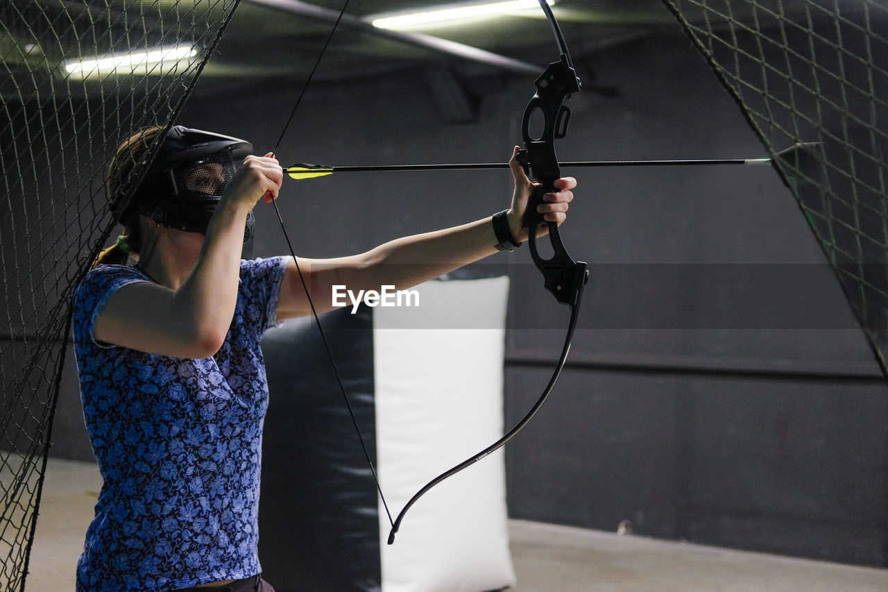 WOMAN HOLDING CAMERA WHILE STANDING BY POLE