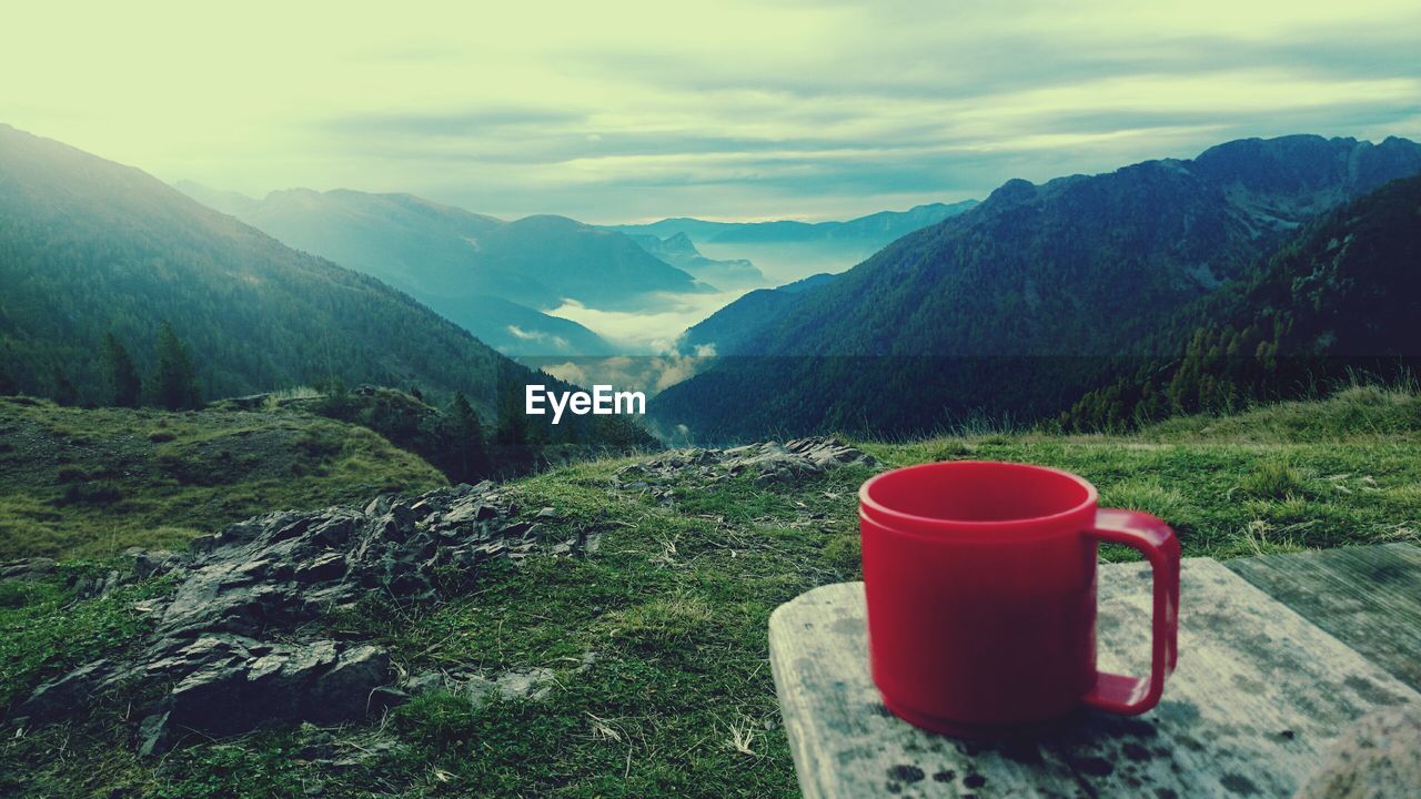 Close-up of red plastic cup on table against mountains