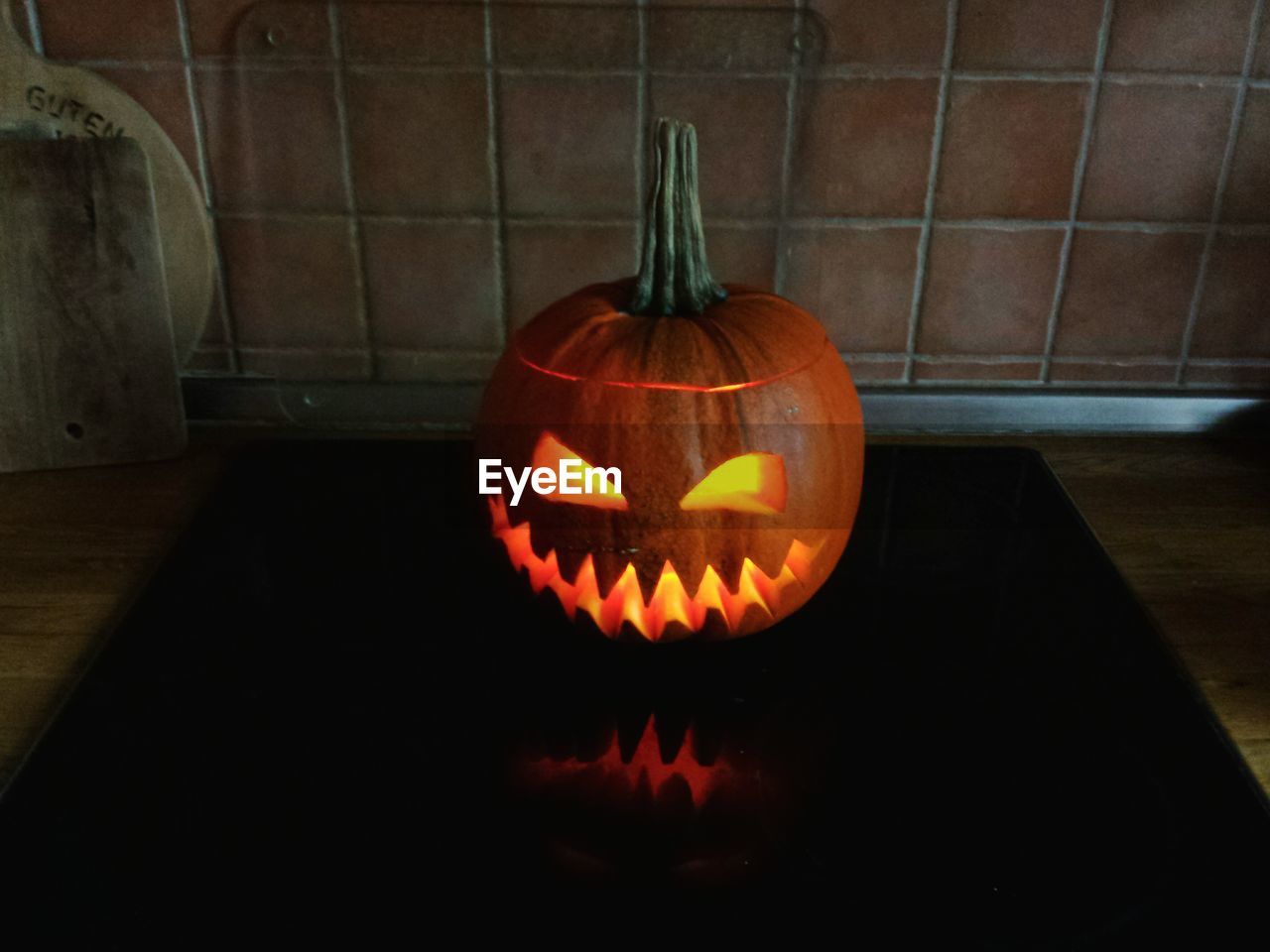 CLOSE-UP OF ILLUMINATED PUMPKIN AGAINST WALL