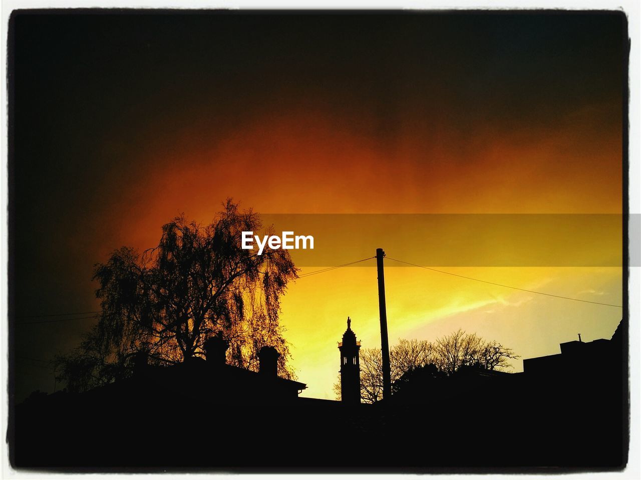 Low angle view of silhouette buildings and trees against sky during sunset