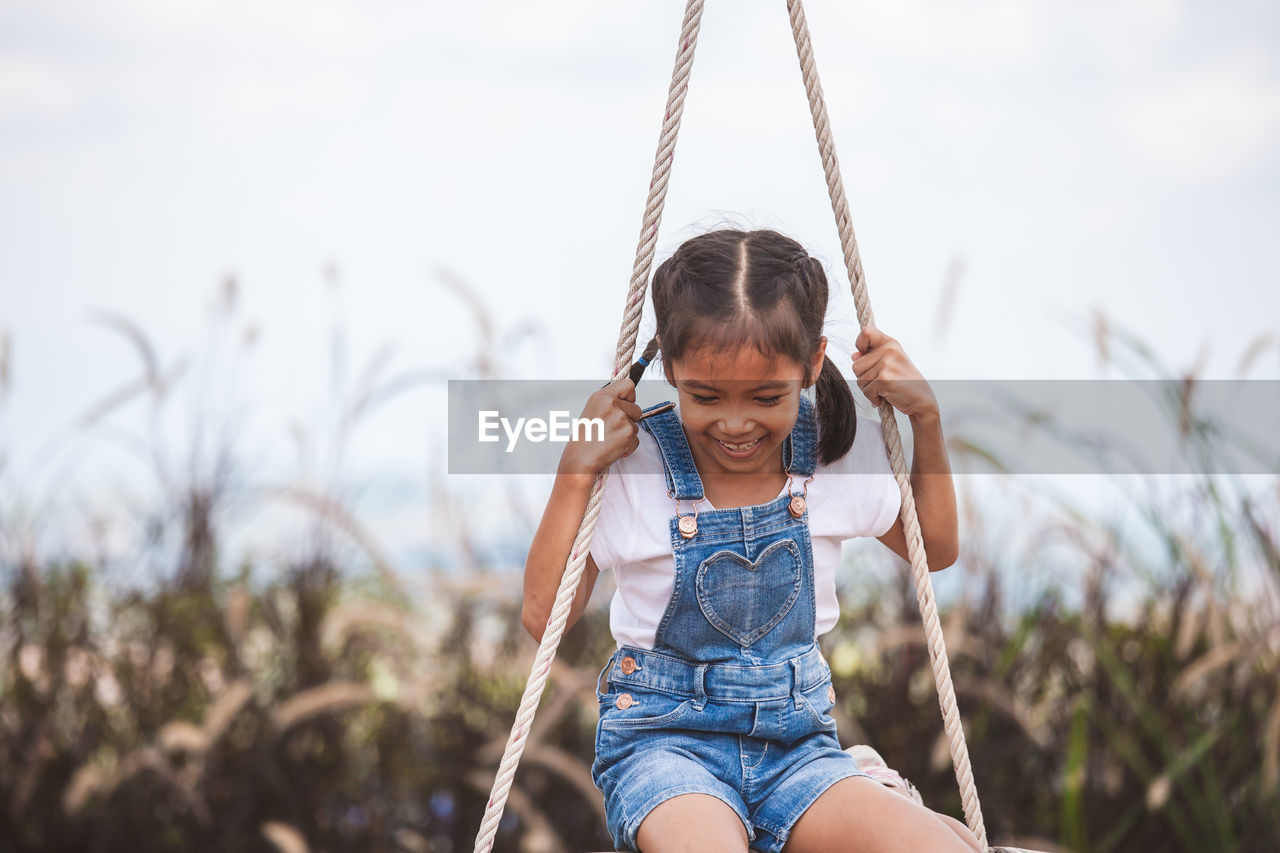 Cheerful girl swinging at playground