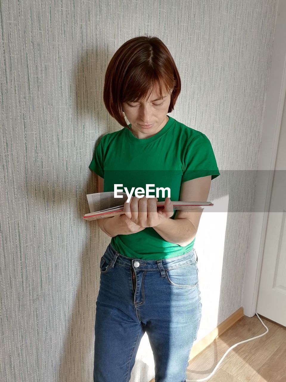 Boy using digital tablet while standing against wall