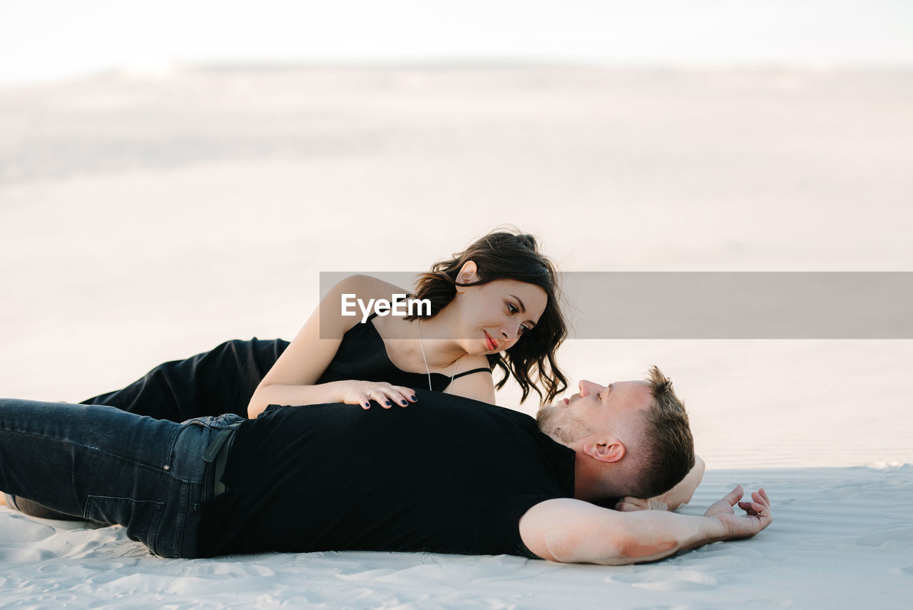 YOUNG WOMAN LYING ON SHORE