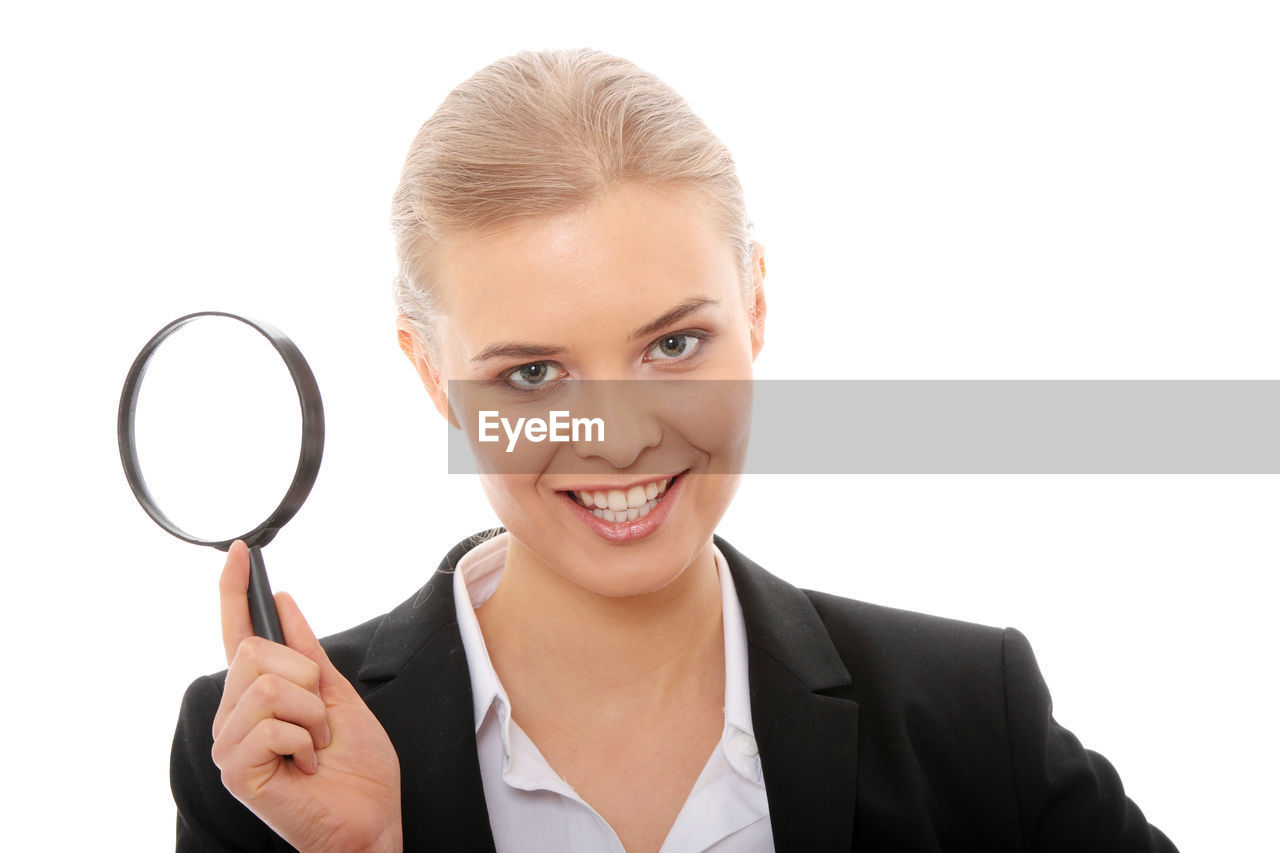 Close-up of businesswoman with magnifying glass against white background