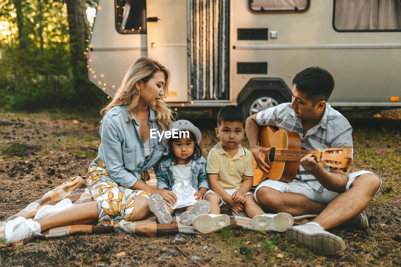 An asian family is vacationing traveling on a road trip by a camper car in the forest in nature