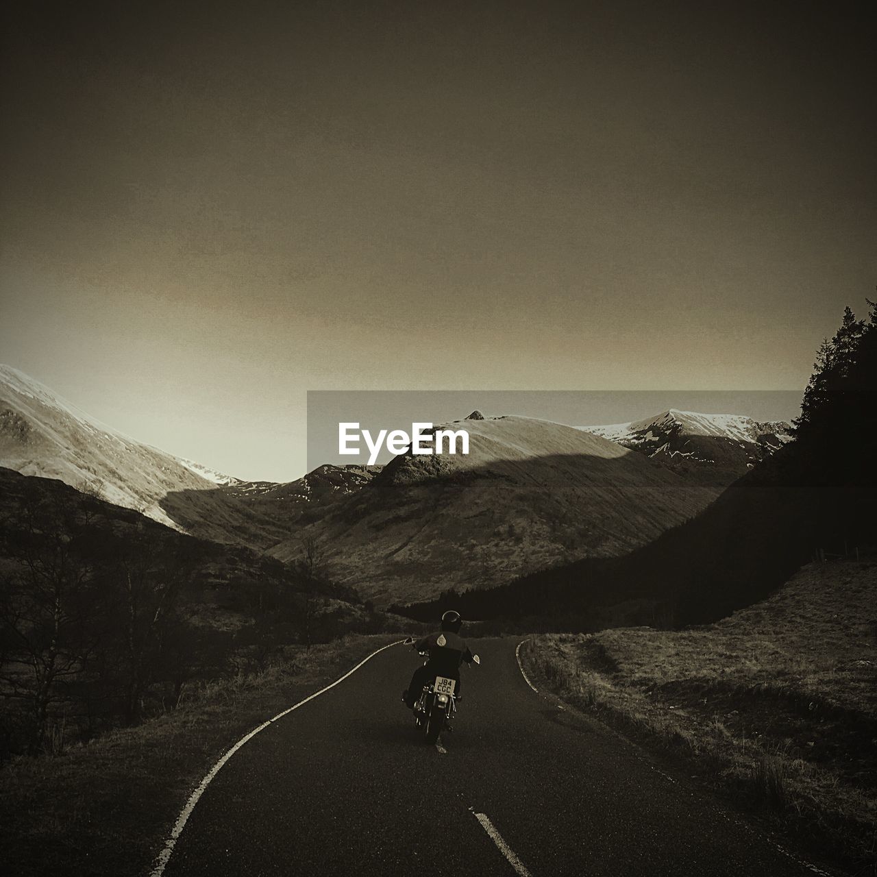 Man riding motorcycle on road against clear sky